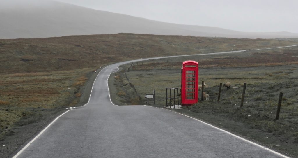A red telephone box sits at the side of a single track road in Shetland, Uk, Mentoring provides an opportunity to stop and talk through the journey.